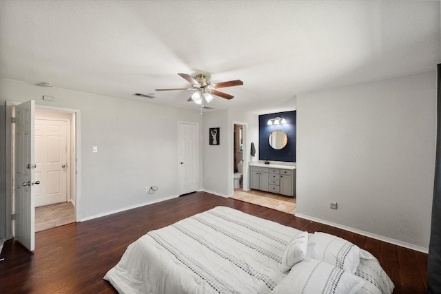 bedroom with visible vents, baseboards, wood finished floors, and ensuite bathroom