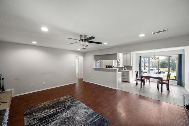 living area with visible vents, ceiling fan with notable chandelier, wood finished floors, recessed lighting, and baseboards