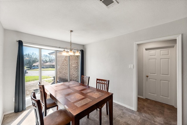 dining space featuring a chandelier, visible vents, a textured ceiling, and baseboards