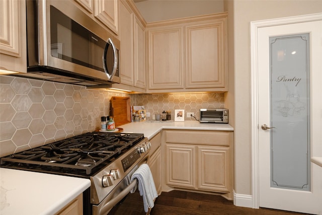 kitchen featuring tasteful backsplash, dark wood finished floors, light countertops, appliances with stainless steel finishes, and cream cabinetry