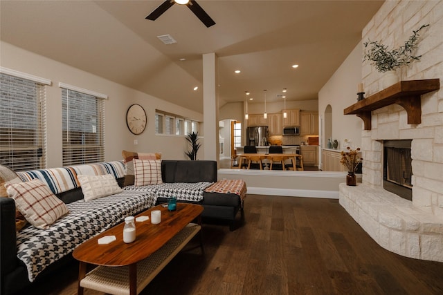 living area with visible vents, wood finished floors, a fireplace, ceiling fan, and vaulted ceiling