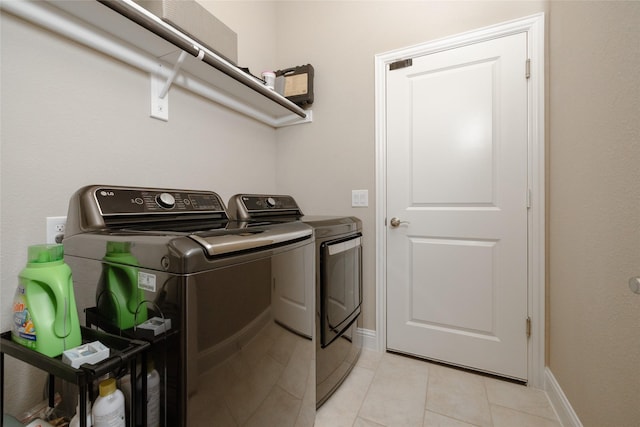 washroom with laundry area, light tile patterned floors, separate washer and dryer, and baseboards