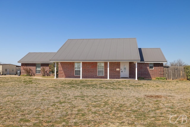 view of front of home with brick siding, metal roof, a front yard, and fence