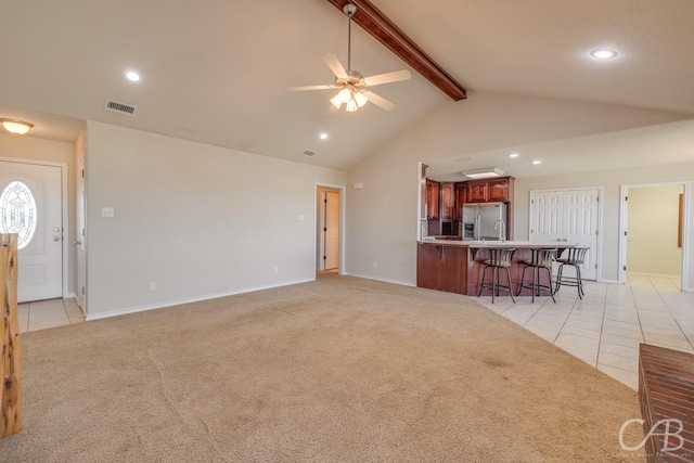 living area featuring beam ceiling, light tile patterned floors, visible vents, and light carpet