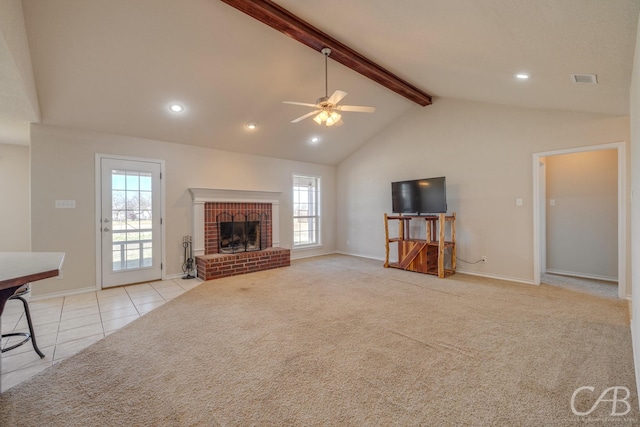 living room with a wealth of natural light, beamed ceiling, light colored carpet, and a fireplace