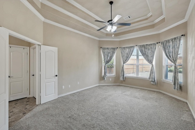 carpeted empty room with a tray ceiling, visible vents, baseboards, and ornamental molding