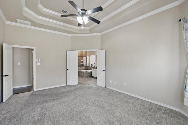 unfurnished bedroom with a raised ceiling, carpet flooring, crown molding, and visible vents