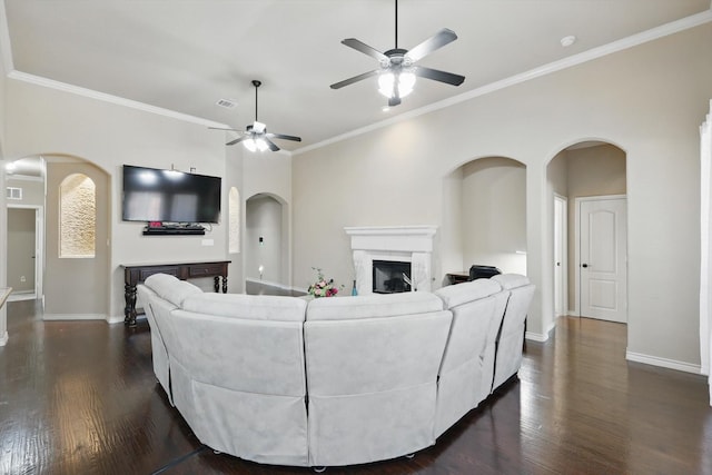 living room featuring dark wood-type flooring, a fireplace, arched walkways, and baseboards