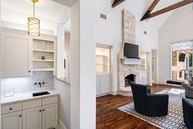 living area with visible vents, baseboards, beam ceiling, a fireplace, and dark wood-style flooring