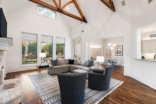 living room with beam ceiling, a healthy amount of sunlight, baseboards, and wood finished floors