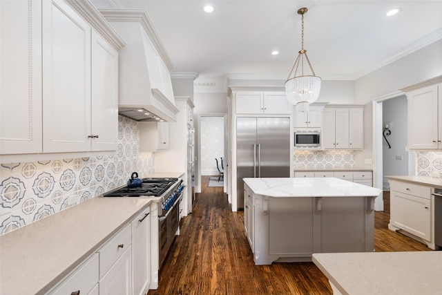 kitchen featuring dark wood finished floors, built in appliances, decorative light fixtures, ornamental molding, and white cabinetry