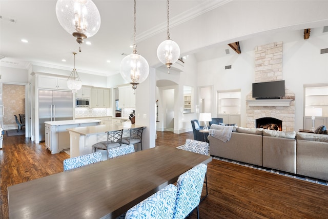 dining area featuring visible vents, a fireplace, dark wood-style flooring, and crown molding