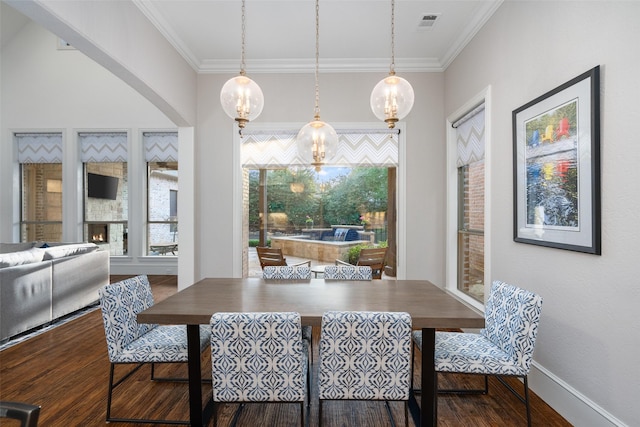 dining room with baseboards, wood finished floors, visible vents, and ornamental molding