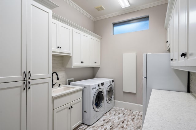 clothes washing area with visible vents, ornamental molding, a sink, washing machine and dryer, and cabinet space