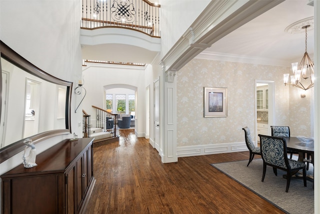 foyer featuring arched walkways, wallpapered walls, an inviting chandelier, and dark wood-style flooring