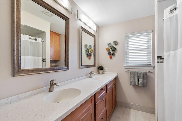 bathroom with double vanity, visible vents, baseboards, and a sink