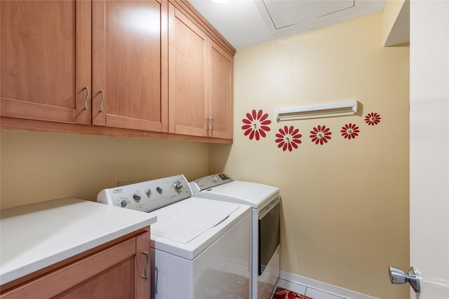 clothes washing area featuring washing machine and dryer, cabinet space, and baseboards