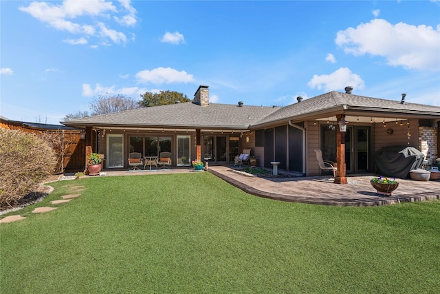 back of property with a yard, fence, a chimney, and a patio area