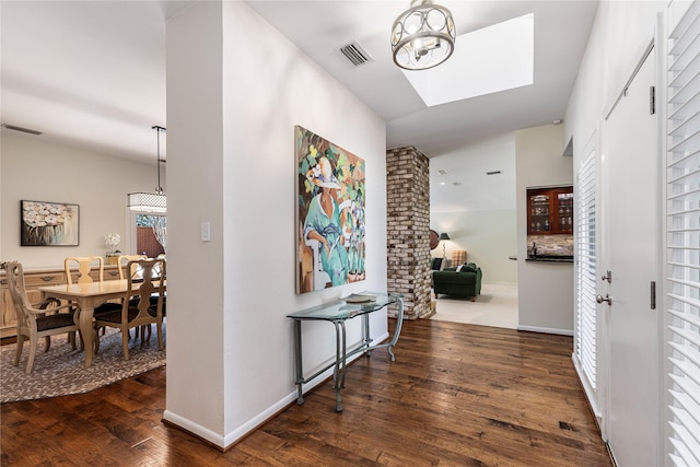 hall with a notable chandelier, visible vents, baseboards, and hardwood / wood-style floors