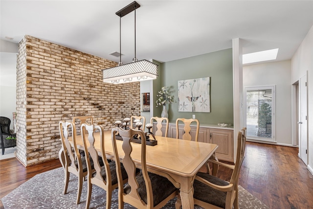 dining space with dark wood finished floors, visible vents, and brick wall