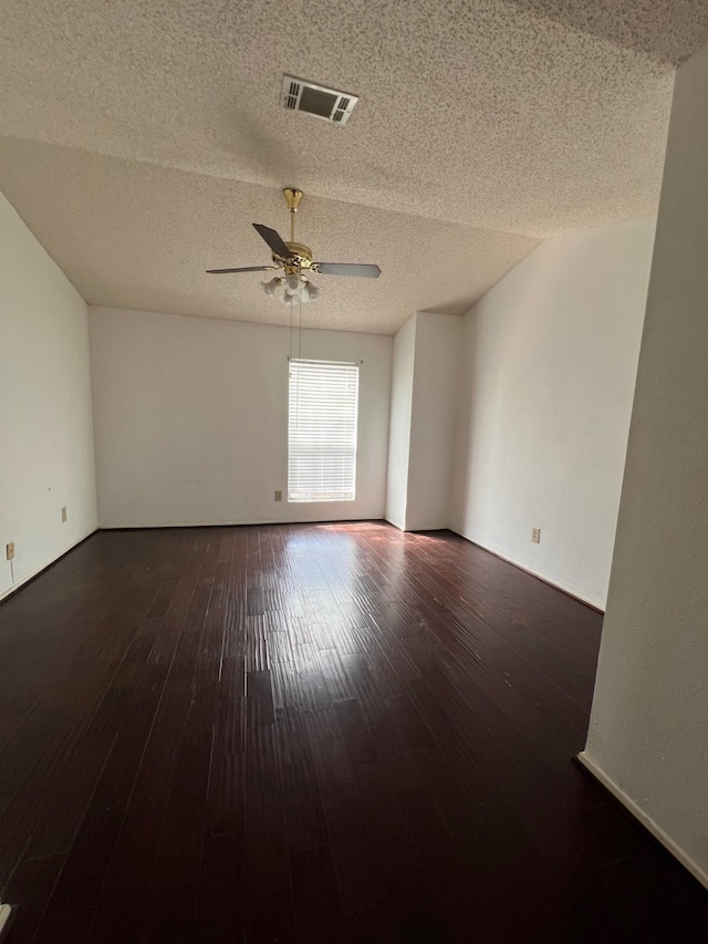 unfurnished room with visible vents, baseboards, hardwood / wood-style flooring, a textured ceiling, and a ceiling fan