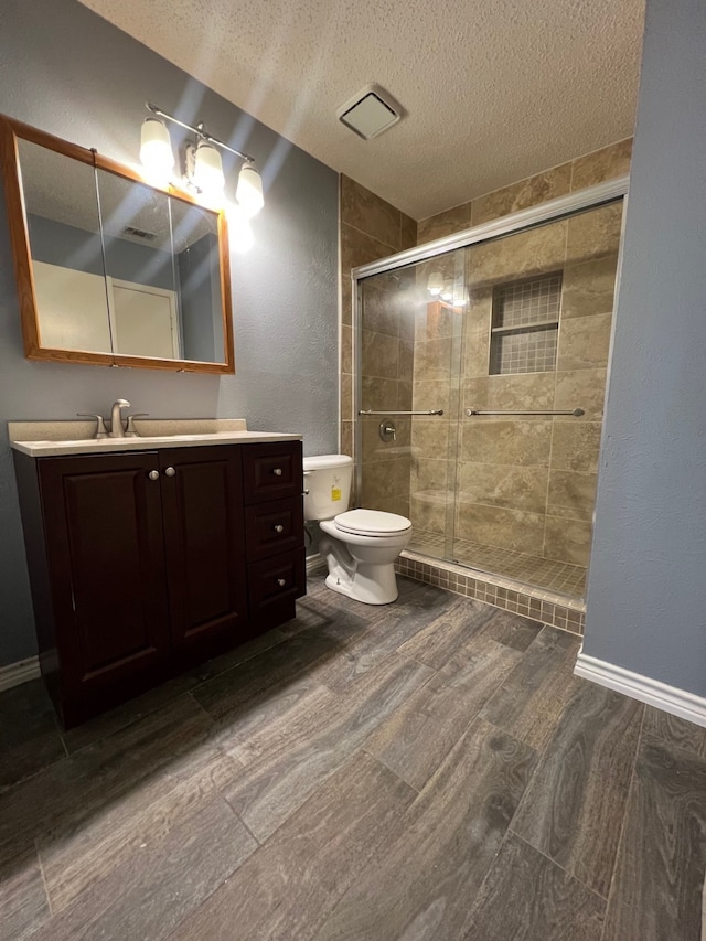 full bath featuring toilet, a stall shower, a textured ceiling, wood finished floors, and vanity