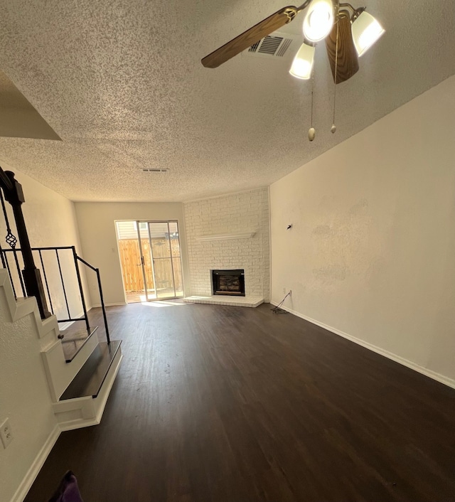 unfurnished living room with visible vents, ceiling fan, stairway, dark wood-style floors, and a textured ceiling