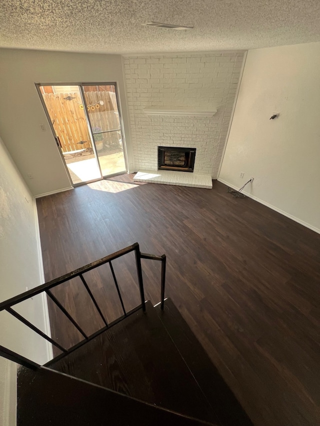 staircase featuring baseboards, a textured ceiling, wood finished floors, and a fireplace