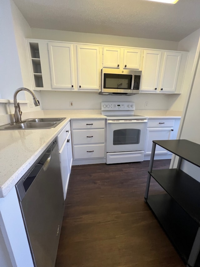 kitchen with dark wood-type flooring, white cabinets, appliances with stainless steel finishes, and a sink