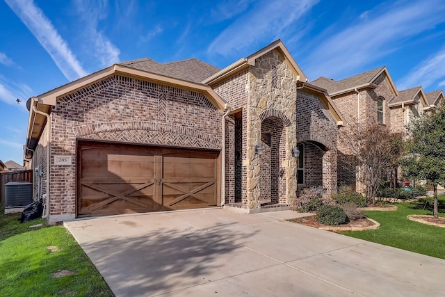 view of front of home with roof with shingles, central air condition unit, an attached garage, driveway, and brick siding