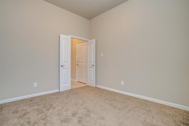 unfurnished room with baseboards and light colored carpet
