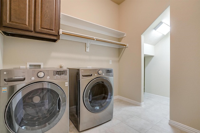 laundry area with washing machine and clothes dryer, baseboards, light tile patterned flooring, and cabinet space