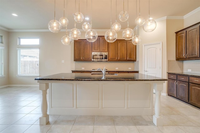 kitchen with stainless steel microwave, crown molding, and dark stone countertops