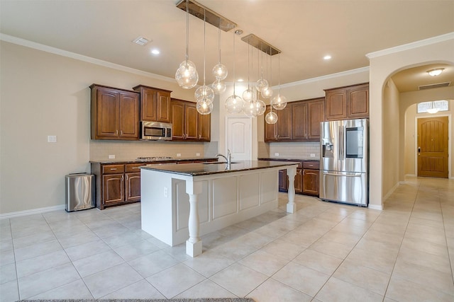 kitchen with visible vents, an island with sink, ornamental molding, arched walkways, and appliances with stainless steel finishes