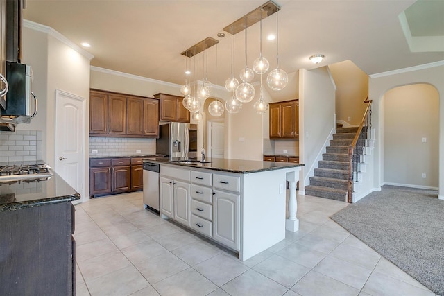 kitchen featuring dark stone countertops, a center island, appliances with stainless steel finishes, and ornamental molding