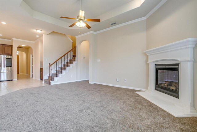 unfurnished living room featuring light colored carpet, arched walkways, stairs, and visible vents