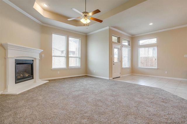 unfurnished living room featuring ornamental molding, a glass covered fireplace, light tile patterned floors, baseboards, and light colored carpet