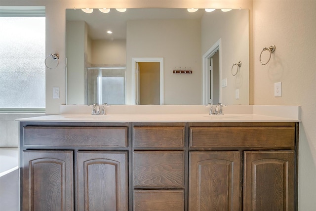 full bathroom featuring double vanity, a healthy amount of sunlight, a stall shower, and a sink