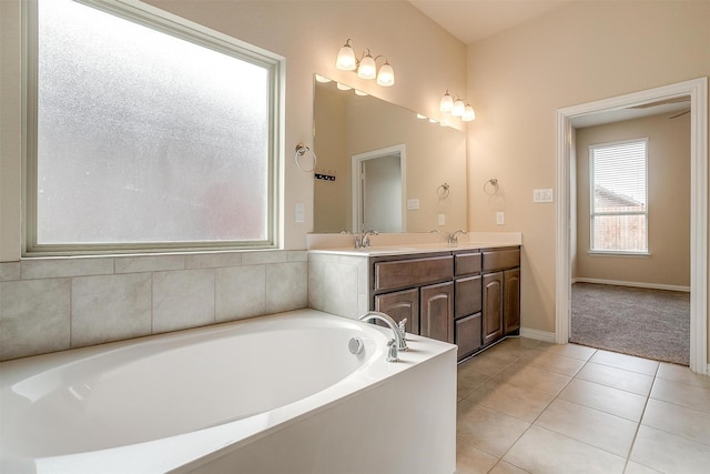 full bath with a garden tub, baseboards, double vanity, a sink, and tile patterned floors