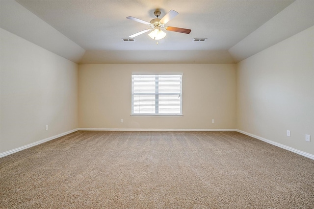 carpeted empty room featuring visible vents, baseboards, ceiling fan, and vaulted ceiling