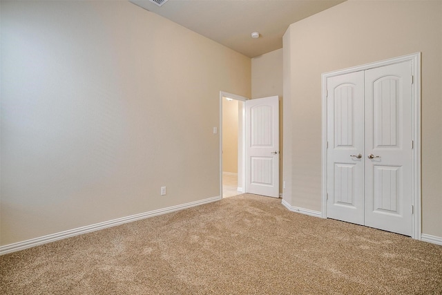 unfurnished bedroom with light colored carpet, baseboards, and a closet