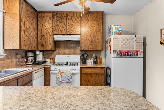 kitchen with white appliances, light countertops, tasteful backsplash, and under cabinet range hood