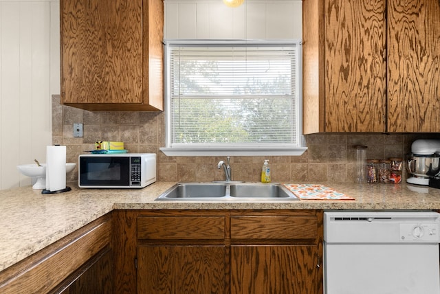 kitchen with white appliances, a sink, light countertops, tasteful backsplash, and brown cabinets