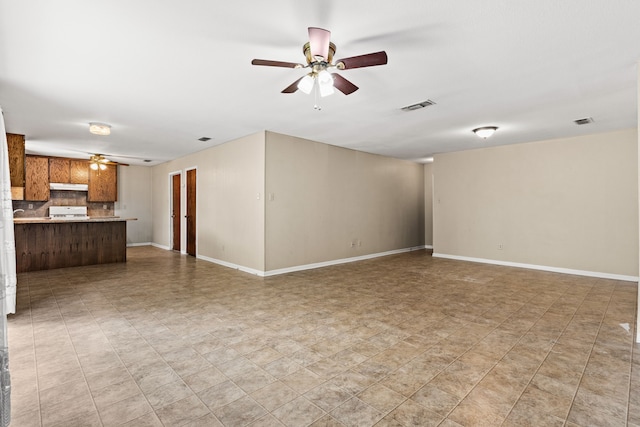 unfurnished living room featuring visible vents, a ceiling fan, and baseboards