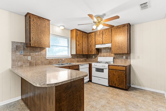 kitchen with under cabinet range hood, visible vents, a sink, white appliances, and a peninsula