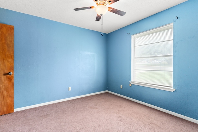 empty room with carpet flooring, a ceiling fan, and baseboards