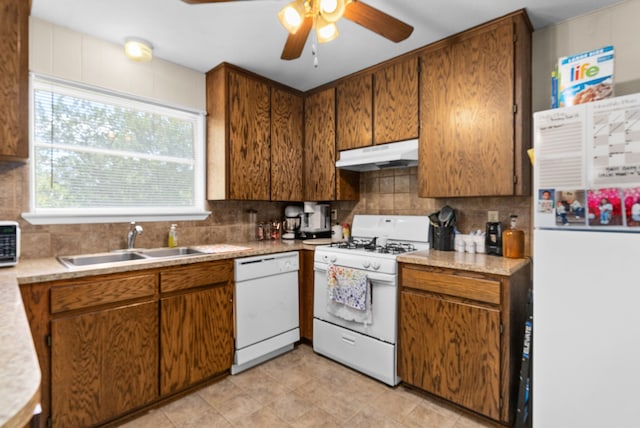 kitchen with a sink, a ceiling fan, white appliances, brown cabinets, and under cabinet range hood