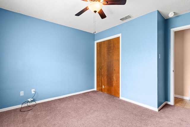 unfurnished bedroom with baseboards, visible vents, a ceiling fan, a closet, and carpet floors