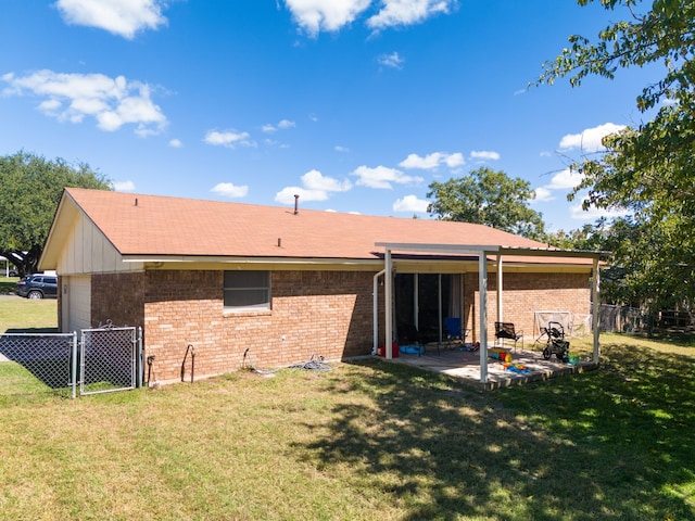 rear view of house with a gate, fence, brick siding, a yard, and a patio