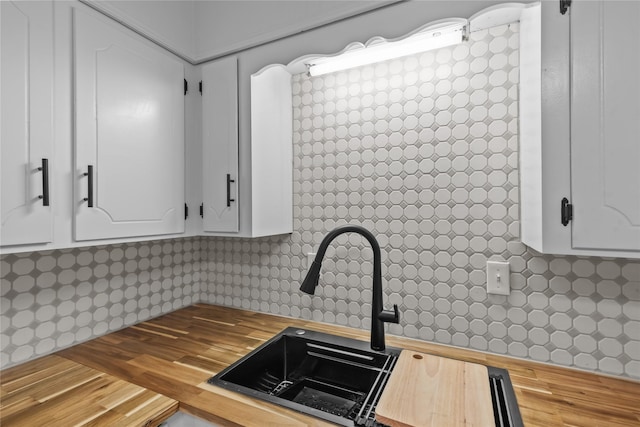 kitchen featuring wood finished floors, a sink, decorative backsplash, butcher block countertops, and white cabinetry